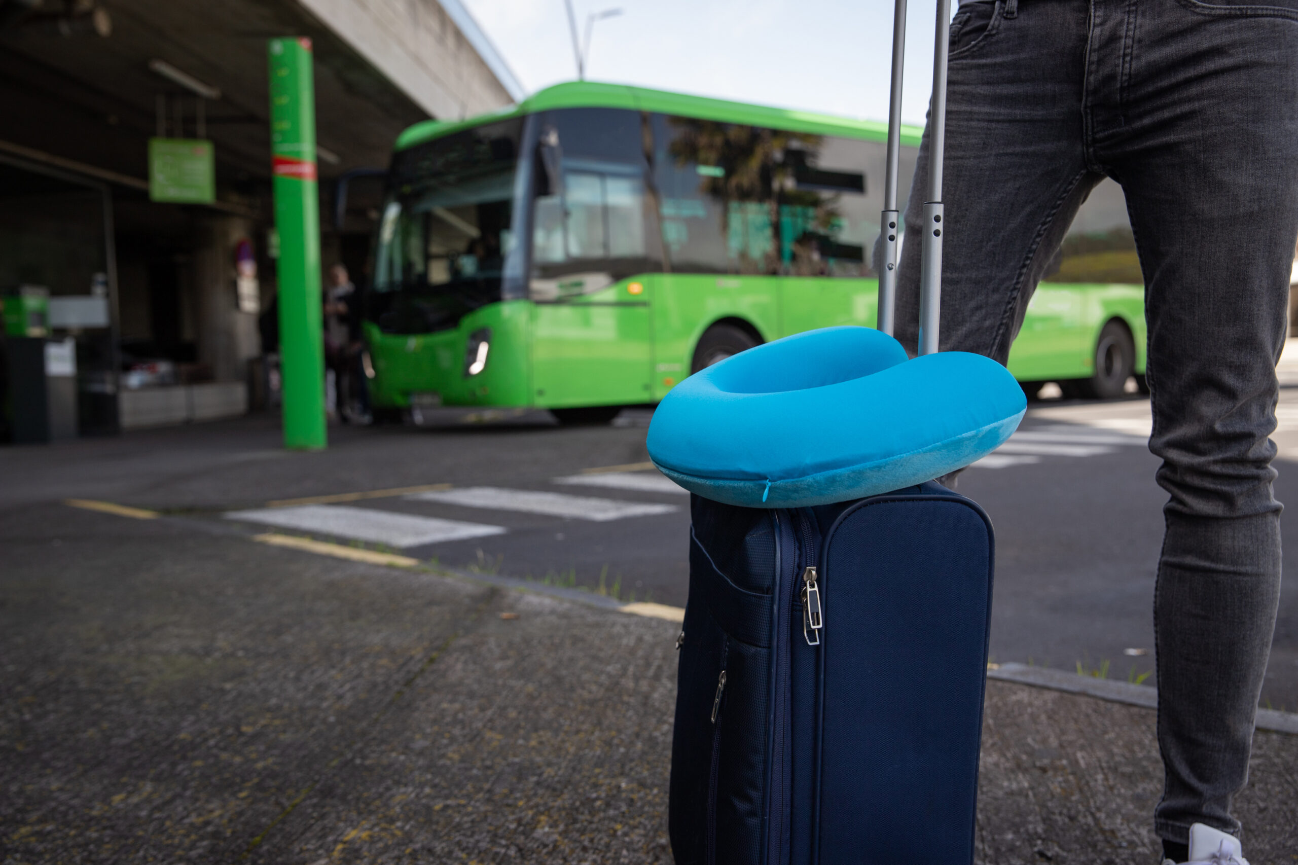Close-up of a traveler's suitcase with the travel pillow on it at the bus station.